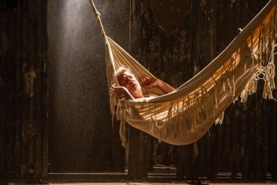 Person relaxing in a hammock with soft light streaming in.