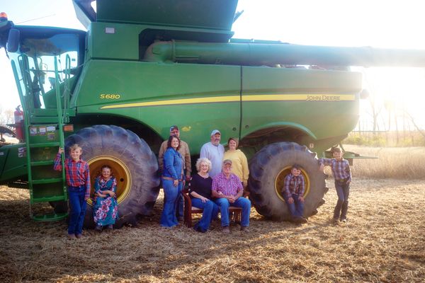 Extended family standing by combine in a field