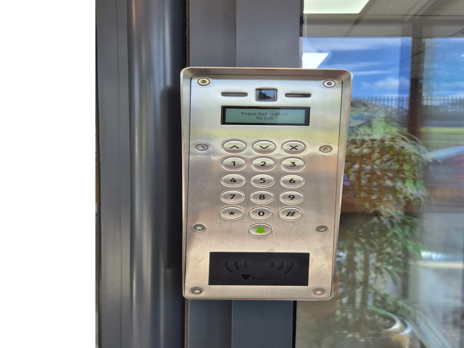 Access control keypad and proximity reader beside a glass entrance door.