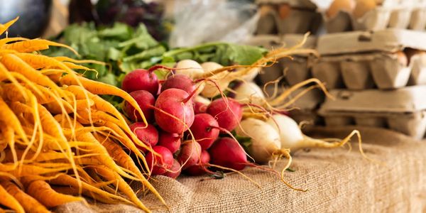 Fresh vegetables and eggs displayed on a rustic market table.