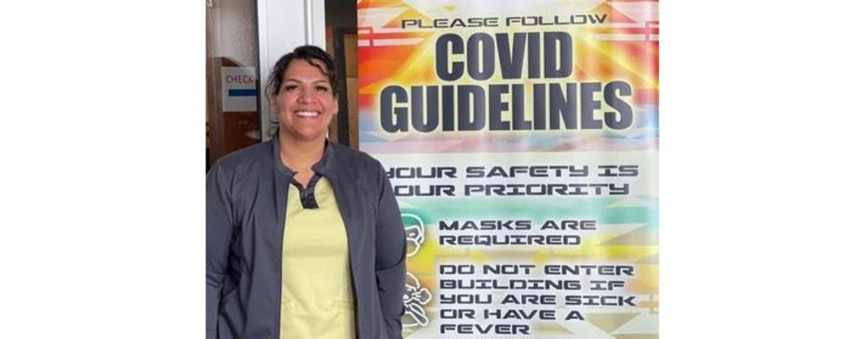A public health nurse next to a poster about COVID guidelines