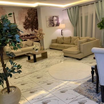 Modern living room with beige sofas, plants, and Paris-themed wall art.