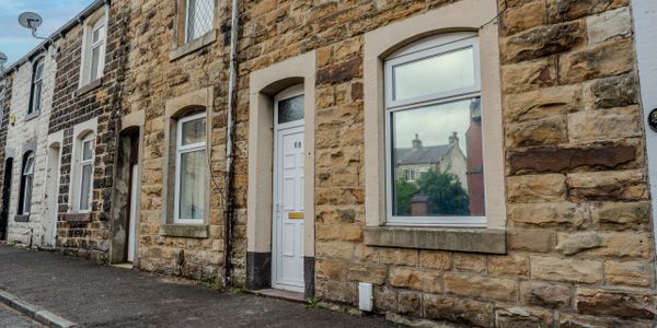 Stone terraced houses with white doors and windows on a quiet street.