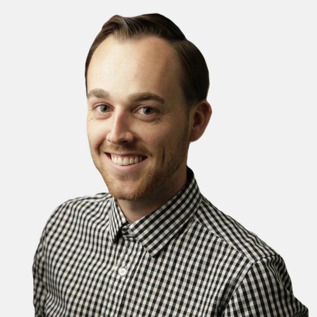 Smiling young man in a black and white checkered shirt against a plain background.
