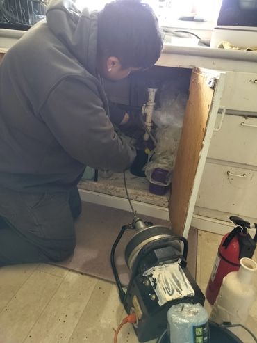 Man using drain snake to open plugged up kitchen sink in Albany Oregon 