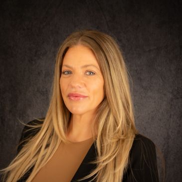 Professional portrait of a smiling woman with long blonde hair against a dark background.