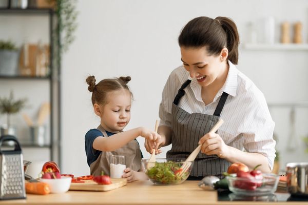 Smiling mother and daughter in aprons, cooking together. CDED diet made fun!