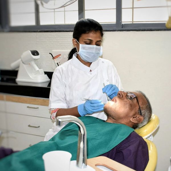 Dentist in Pune examining an elderly man's teeth and offering dental care