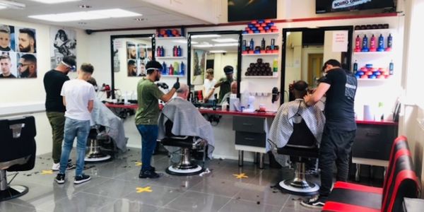 Barbers giving haircuts to customers in a modern barbershop.