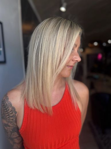 Blonde woman in a red top with tattooed arm.