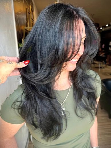 Smiling woman with long, layered black hair.