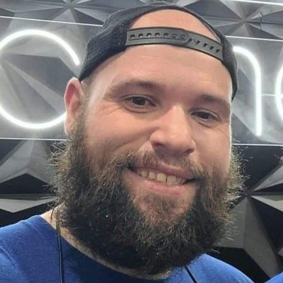 A smiling man with a beard and backward cap.
