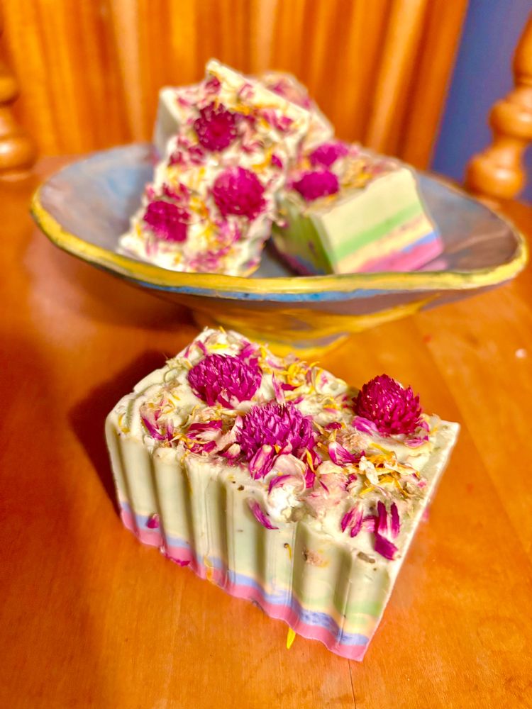 Colorful handmade soaps with dried flowers on a wooden table.