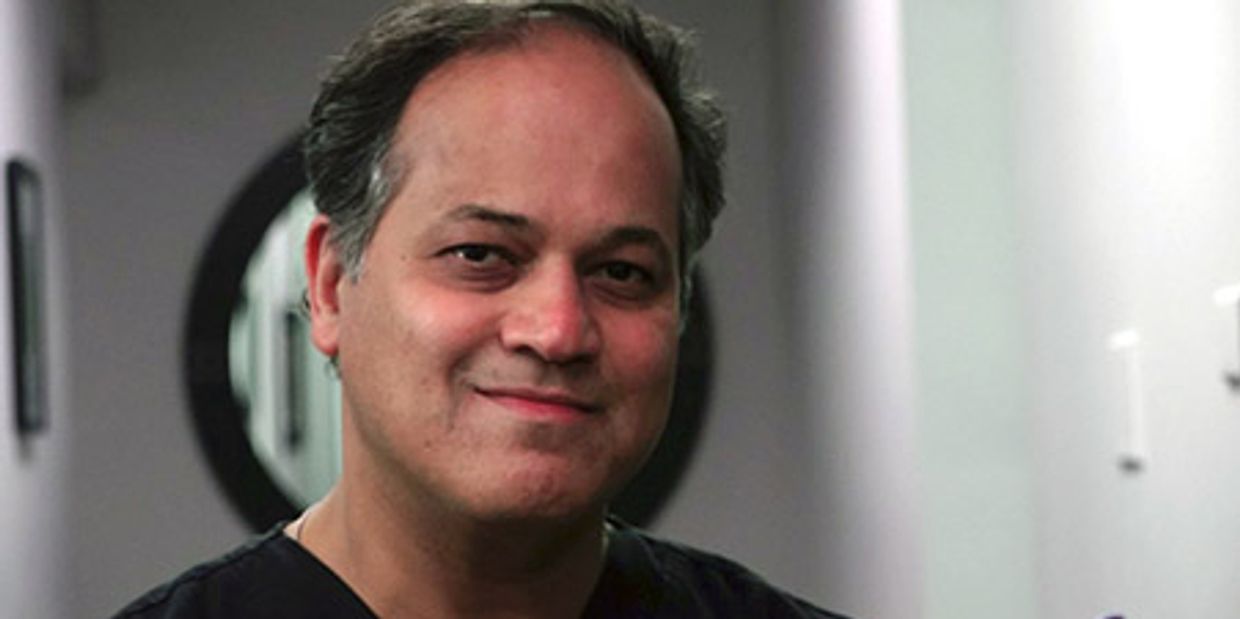 Middle-aged man smiling warmly in a professional setting.