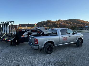 Silver pickup truck towing a large flatbed trailer with metal frames.