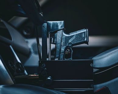 A handgun secured in a vehicle gun safe between car seats.