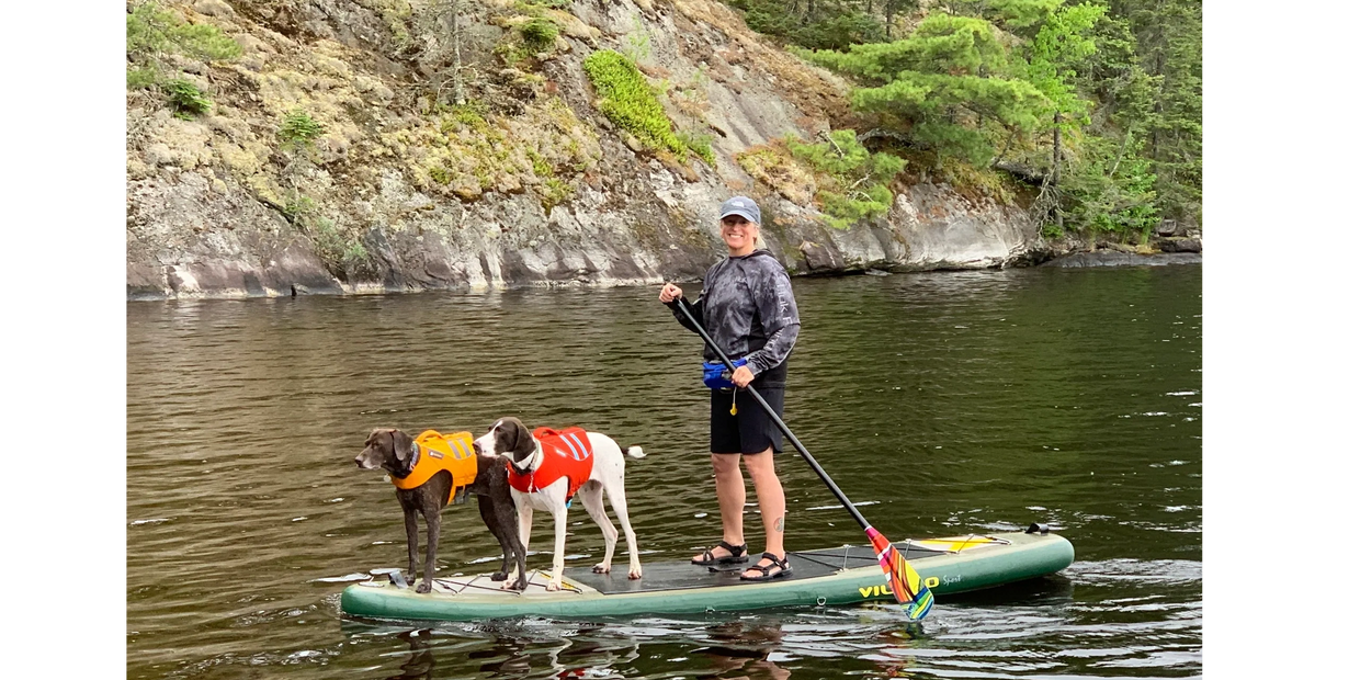 Dr. Lisa paddleboarding with her beloved pups, Una and Grace, in Voyageur National Park.