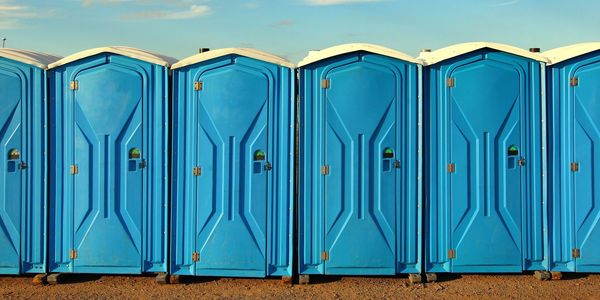 Row of blue portable toilets outdoors.