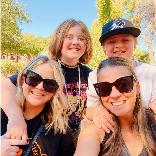 Four smiling people outdoors on a sunny day.