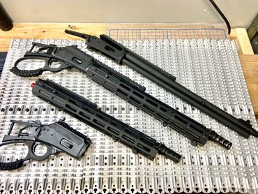 Mad Pig Tracker rifles in various starges of completion sitting on top the taw XS Sight extended opt