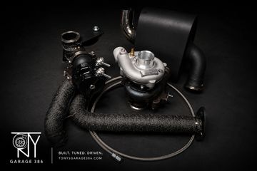 Car turbocharger with pipes and hose on black background.