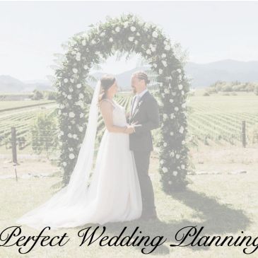 Bride and groom under floral arch at outdoor wedding.