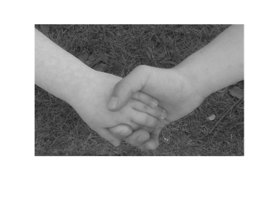 Two people holding hands on grass.