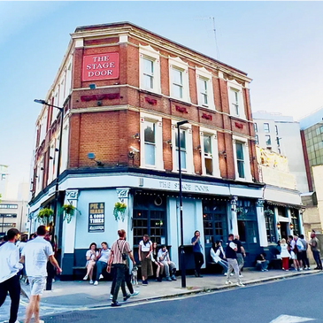 People gather outside The Stage Door pub on a sunny day.
