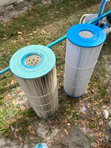 Two cylindrical pool filters on grass, one clean and one dirty.