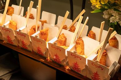 Fried spring rolls in paper holders with chopsticks.