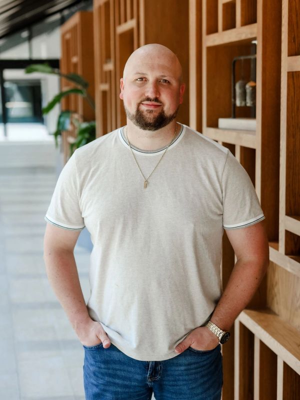 Man with a beard wearing a white t-shirt and jeans.
