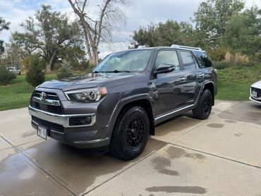 Gray Toyota 4Runner parked on a driveway with wet patches on the concrete.