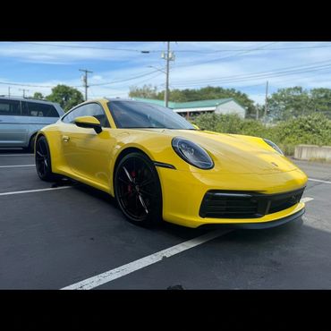 Yellow Porsche sports car parked in an outdoor lot on a sunny day.