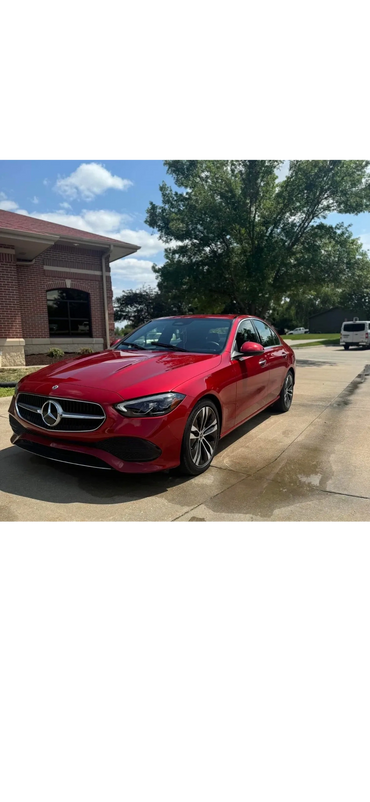 A shiny red Mercedes-Benz sedan parked on a sunny driveway.