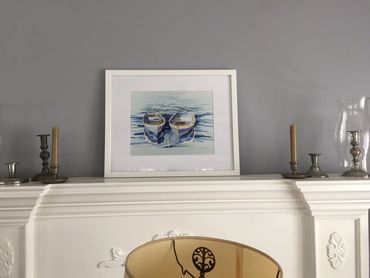 Watercolor art blue boats on mantle in beach home on living room wall.