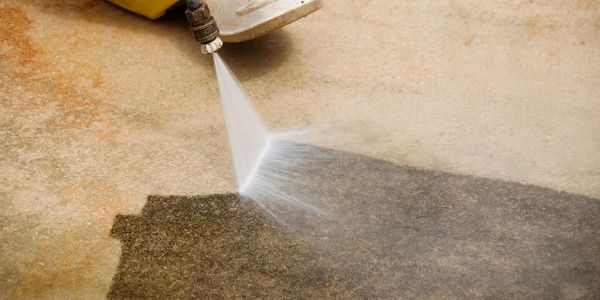 Maintenance Worker Cleaning Dirty Driveway With a Pressure Washer