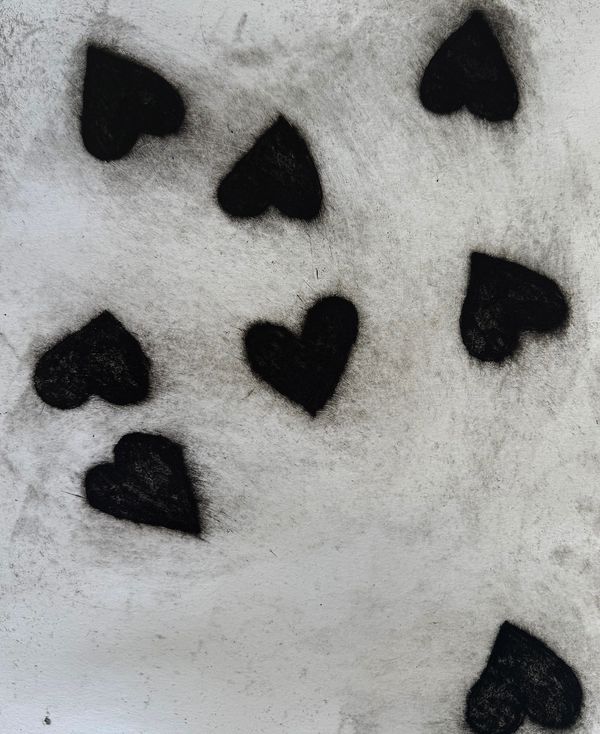 Black heart shapes spray-painted on a white textured wall.