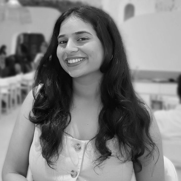 Smiling woman with long hair in a white top, captured in a black and white photo.