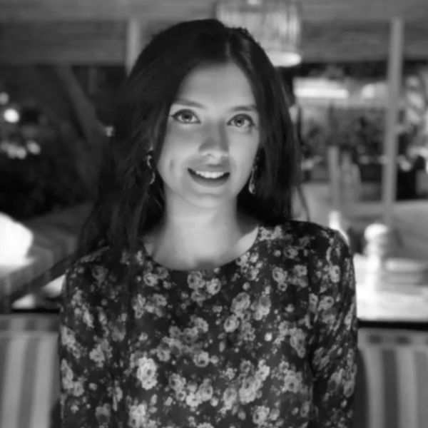 Smiling woman in floral dress with dimples, captured in black and white.