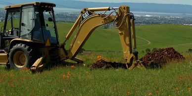 Backhoe digging a soil profile hole for septic system feasibility in Carmel Valley, CA