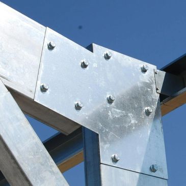 Close-up of a metal joint with bolts against a clear blue sky.