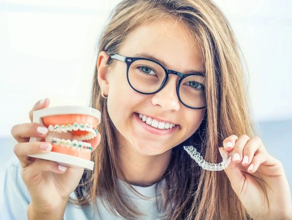 Girl showing her beautiful smile after using orthodontics or Invisalign