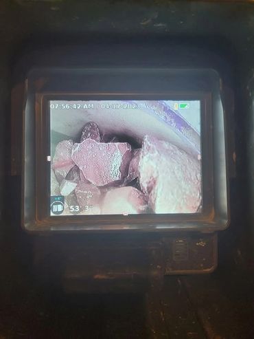 Camera view showing rocks inside a pipe or confined space.
