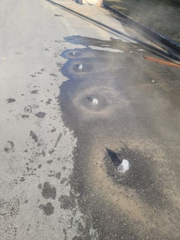 Water bubbling up through holes in a paved road.