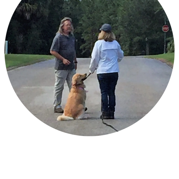 man giving instructions to woman and her leashed golden retriever 