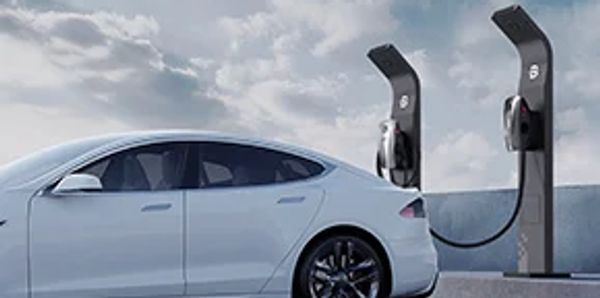 A white electric vehicle is charging at an EV station