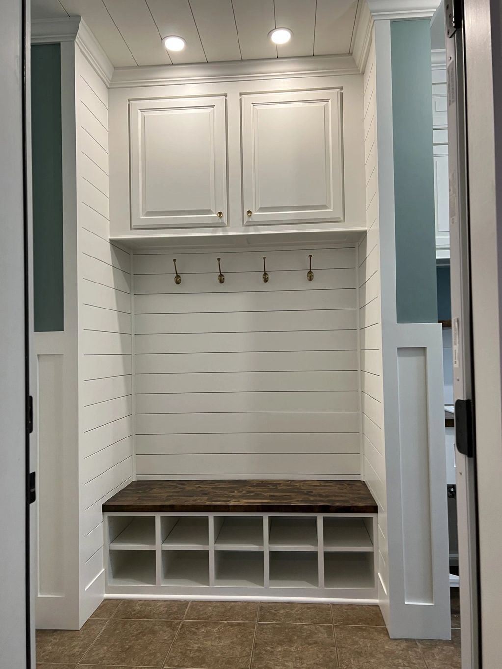 Finished mudroom with shiplap, bench nook, and coat hooks
