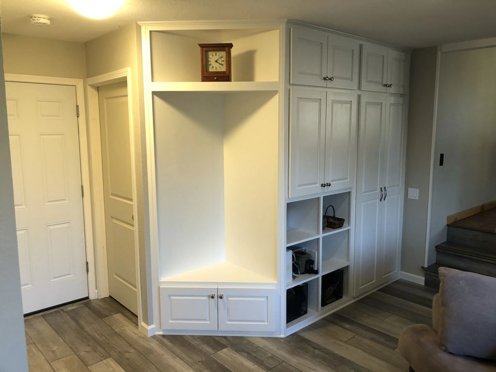 White built-in storage wall with a coat closet, bench nook, and cubbies