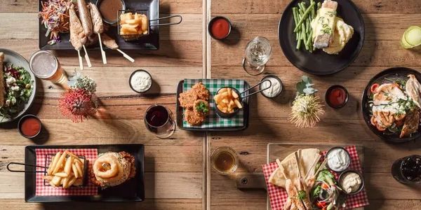 A wooden table with various plates of food and drinks arranged neatly.