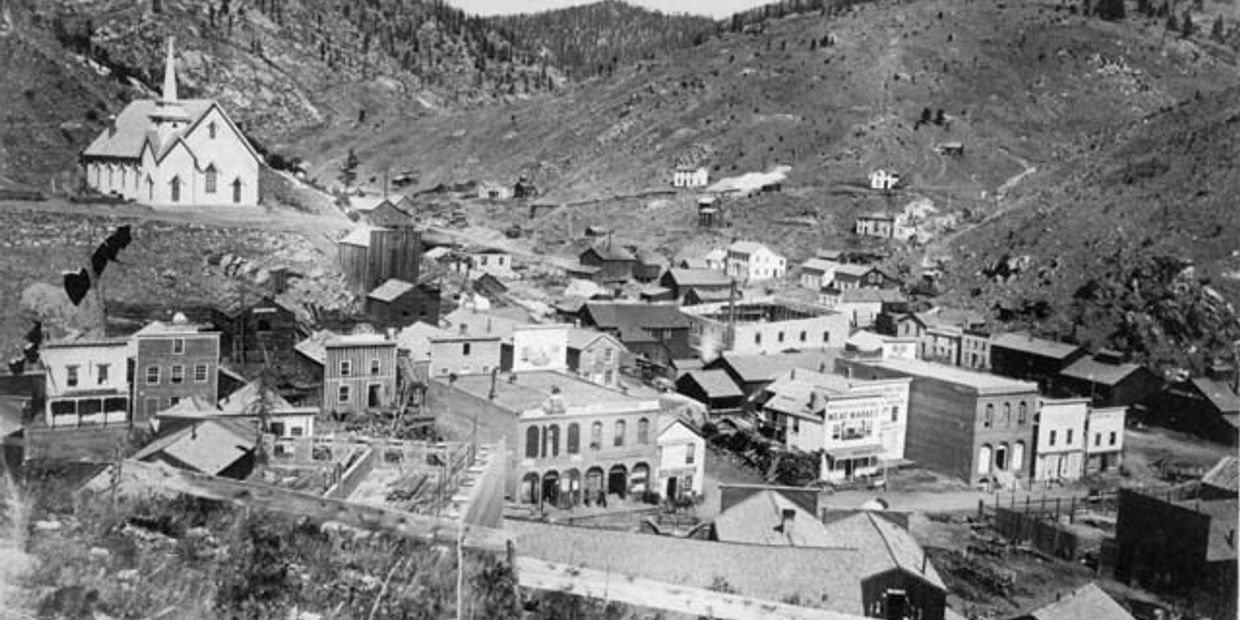 Black and white photo of an old mountain town with a church.